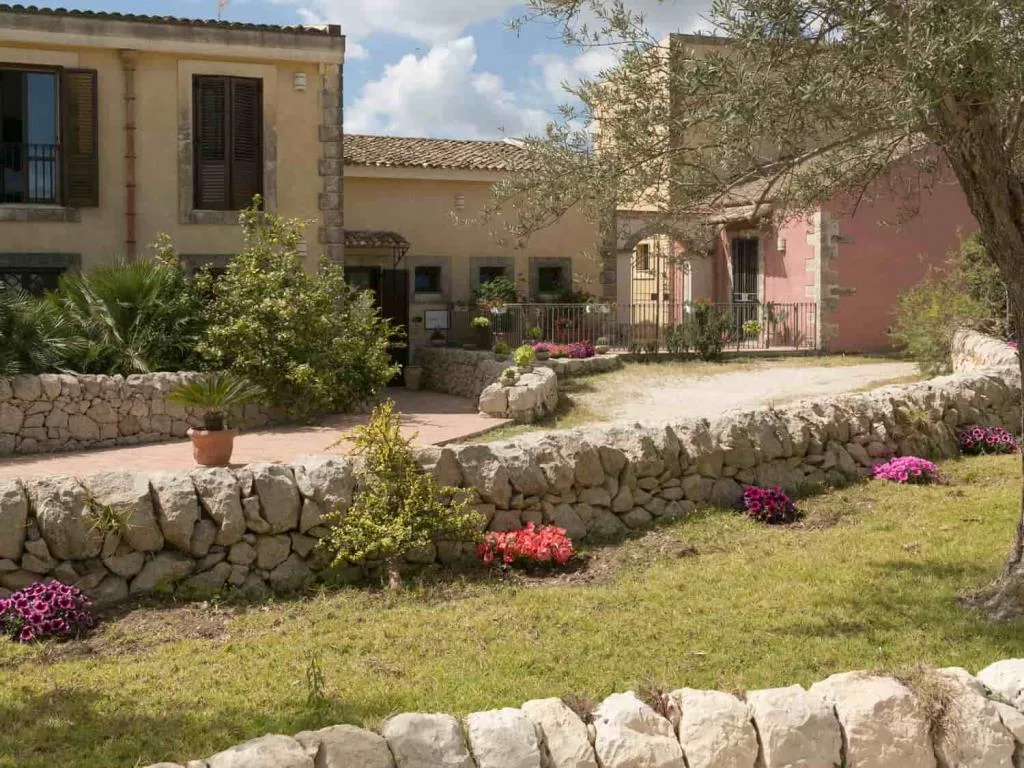 Edifici storici in pietra con giardino fiorito, muretti a secco e vialetto d'ingresso