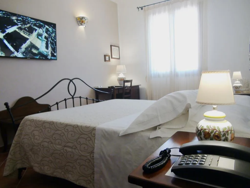 Camera da letto con letto in ferro battuto, TV a parete, scrivania e lampada in ceramica dipinta