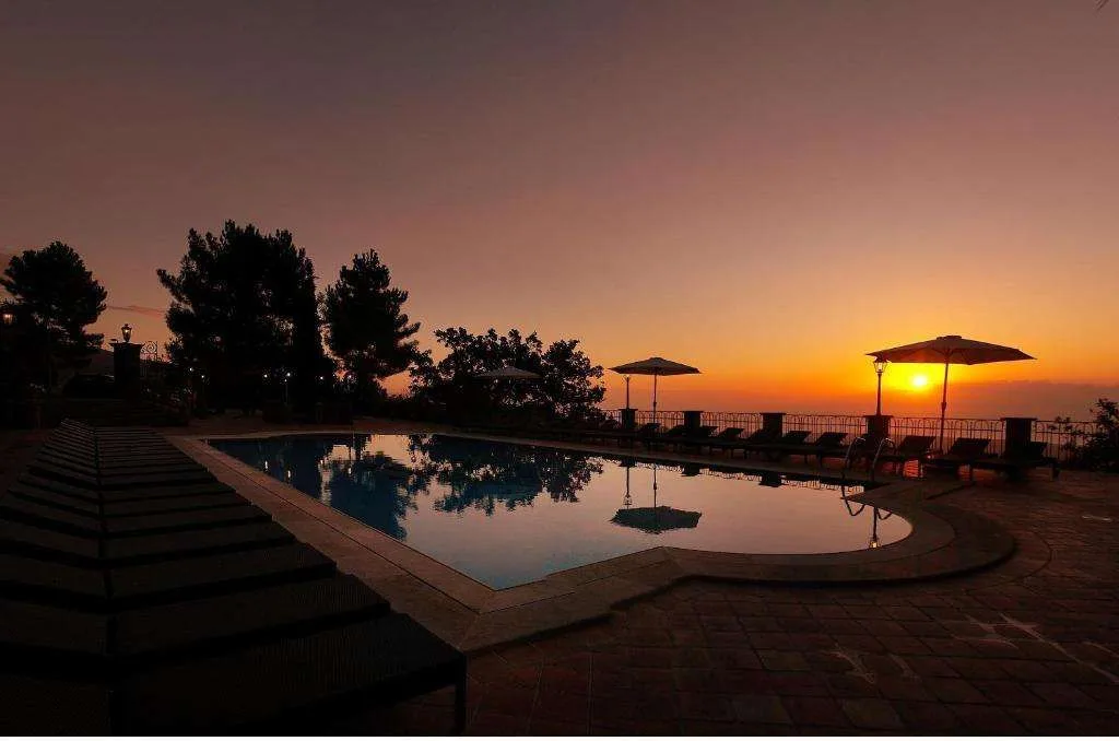 Piscina all'aperto al tramonto con vista panoramica sul mare