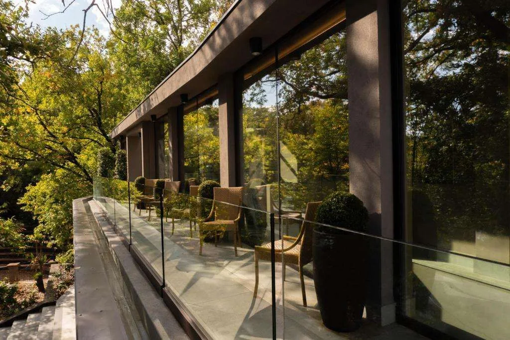 Terrazza coperta con poltrone in vimini e vetrate affacciate sul verde