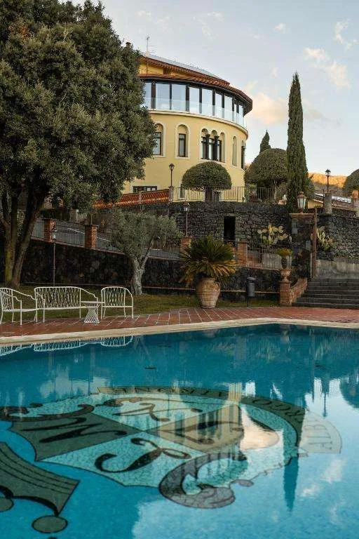 Piscina esterna con mosaico decorativo e vista sull'edificio storico dell'hotel