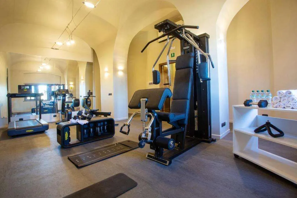 Palestra attrezzata con macchinari, tapis roulant e pesi sotto soffitti a volta