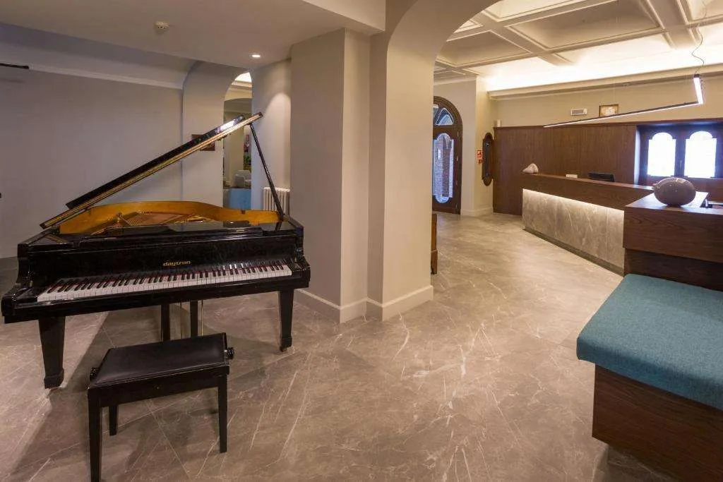 Hall elegante con pianoforte a coda e reception in legno