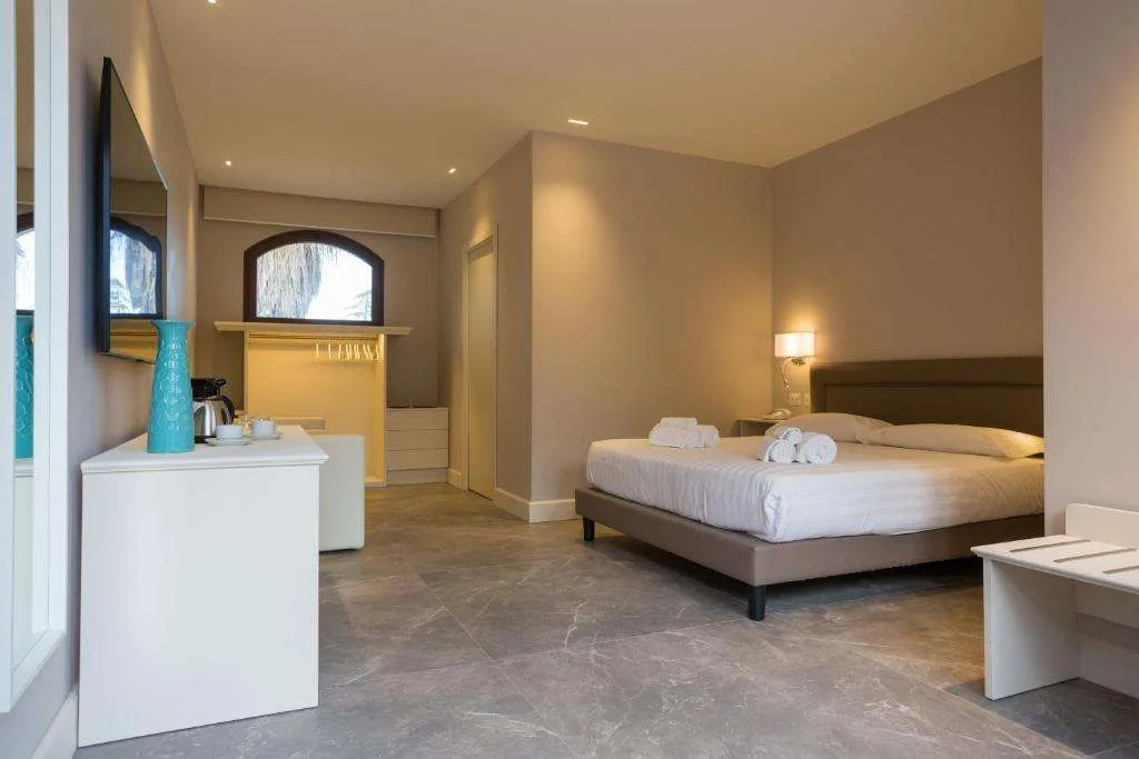 Camera spaziosa con letto matrimoniale, angolo caffè e pavimento in marmo