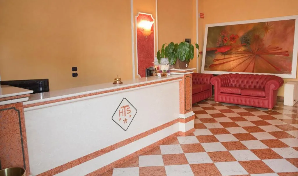Reception dell'hotel con bancone in marmo, divano in pelle rossa e quadro decorativo