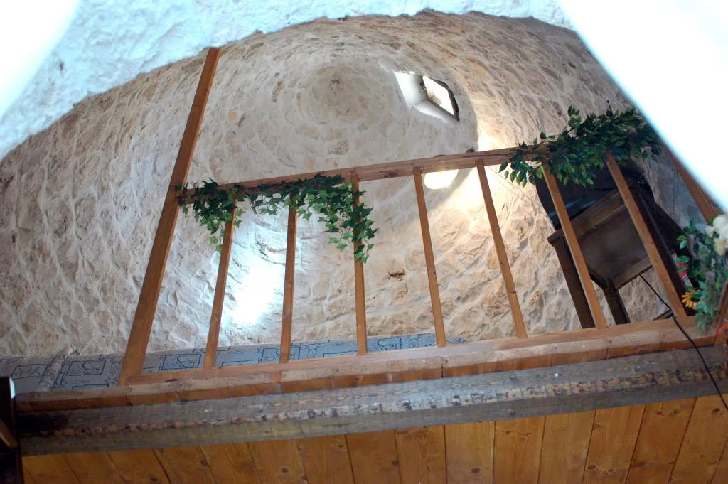 Dettaglio della volta in pietra di trullo con balaustra in legno e piante decorative