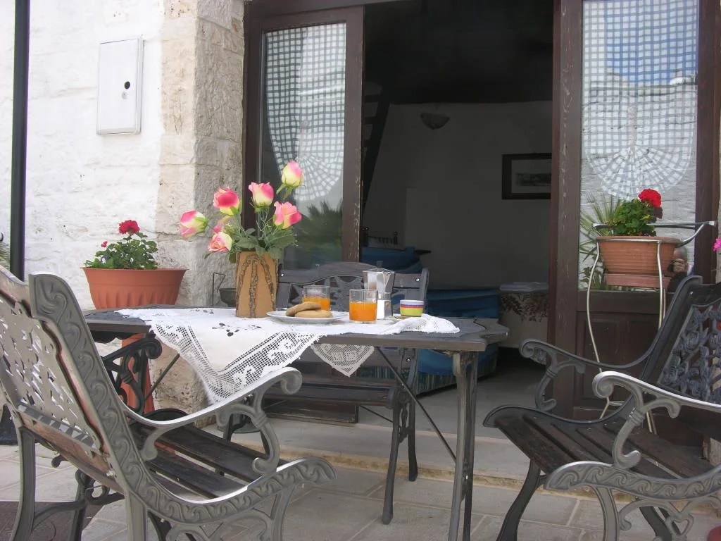 Colazione servita su tavolo in terrazza con fiori e sedie in ferro battuto