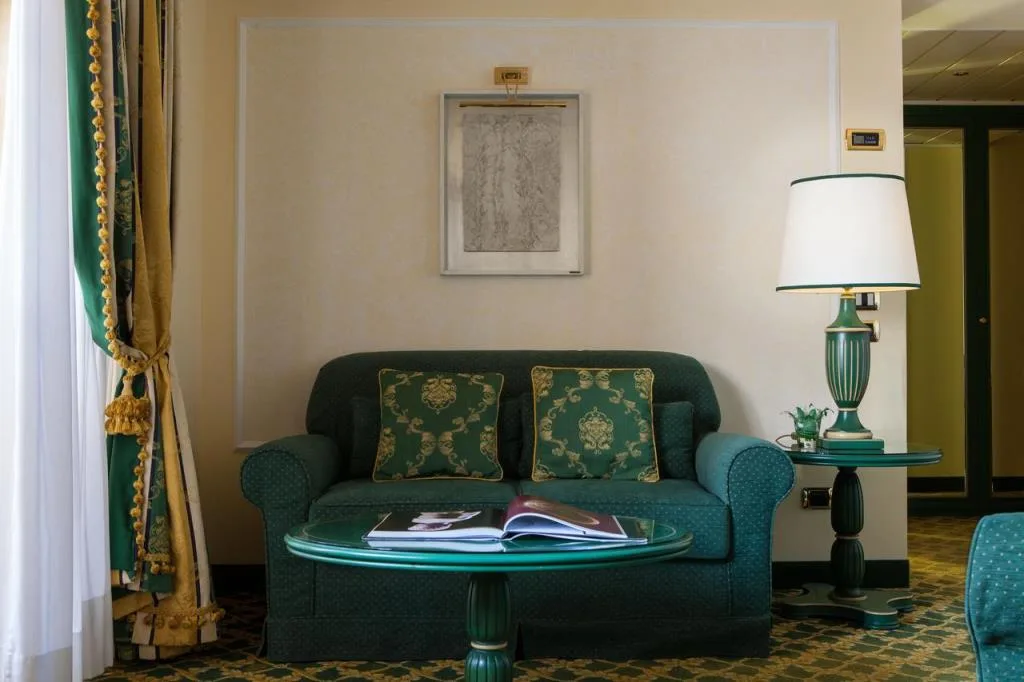 Angolo relax con divano verde damascato, lampada e tende con nappe dorate
