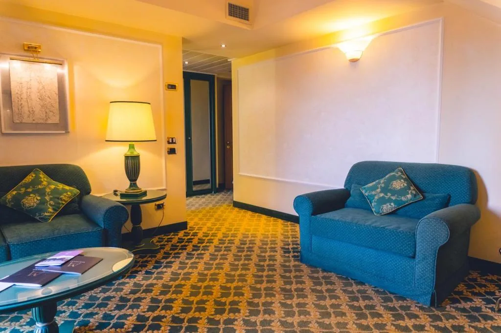 Salottino con poltrone blu, cuscini decorati e moquette a motivi geometrici
