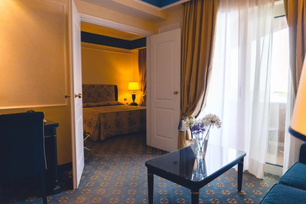 Suite con soggiorno e camera da letto comunicante, tende dorate e fiori sul tavolo