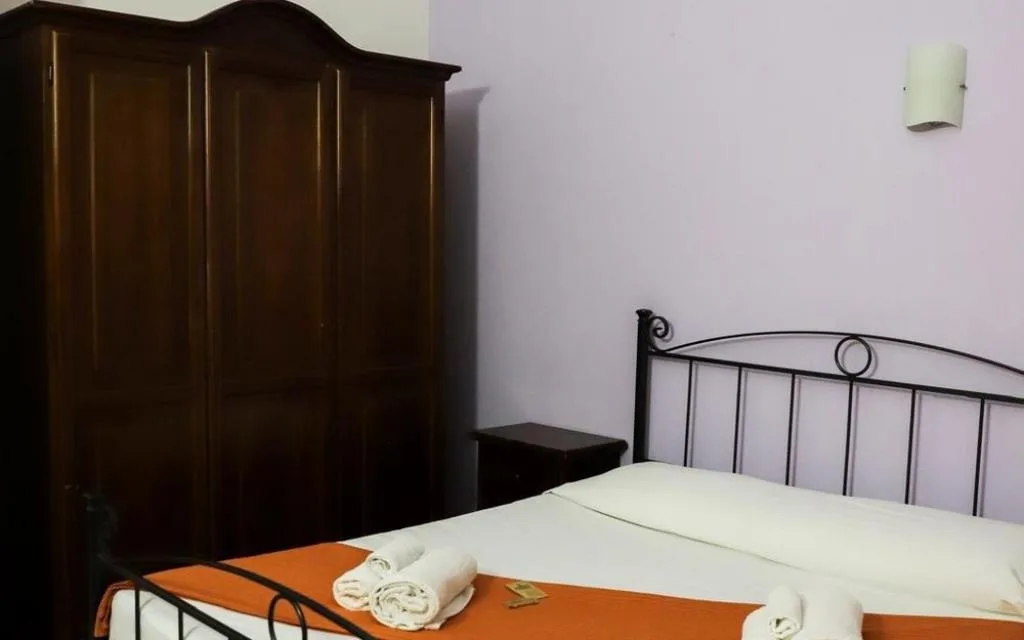Camera con letto in ferro battuto, armadio in legno scuro e asciugamani