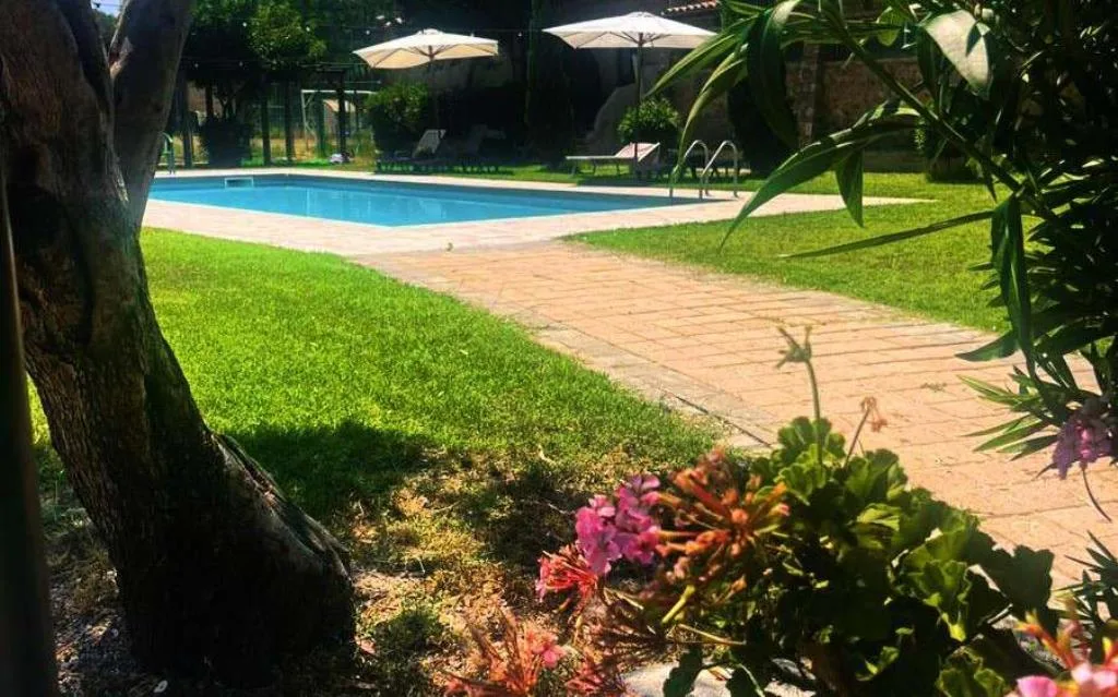 Piscina esterna con lettini, ombrelloni e giardino curato con fiori