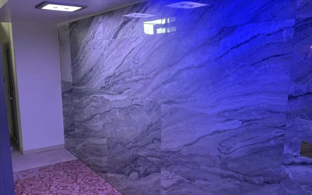 Zona spa con parete rivestita in marmo e illuminazione blu suggestiva