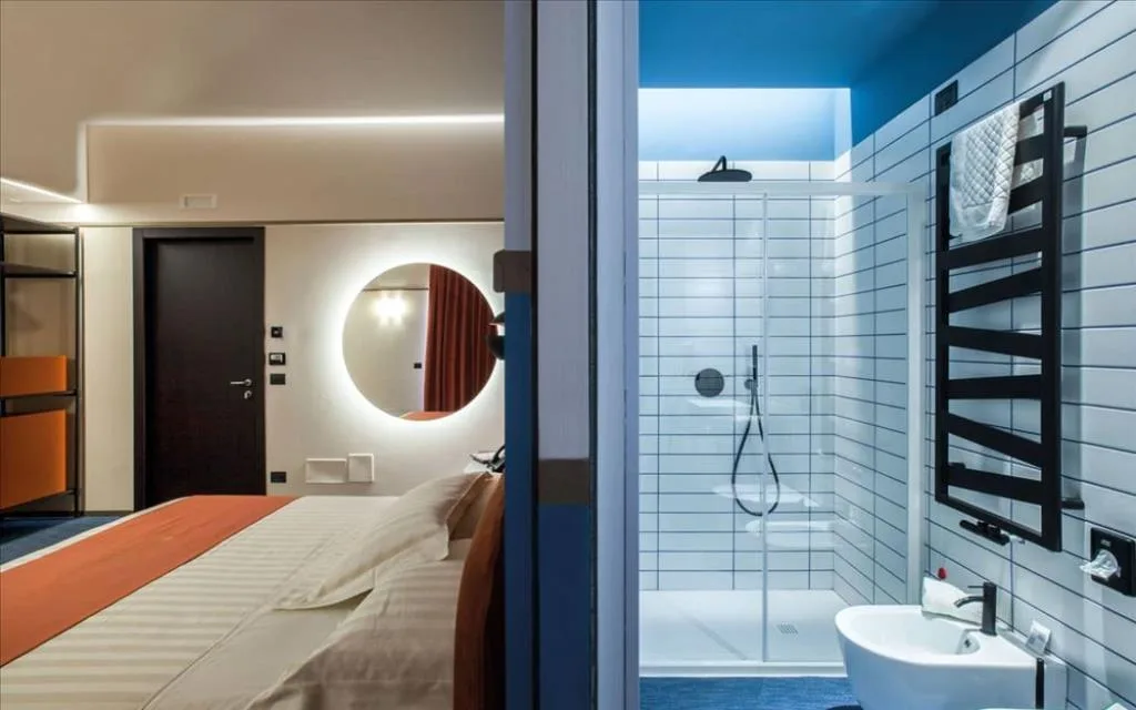 Camera con vista sul bagno moderno dotato di doccia, bidet e piastrelle bianche