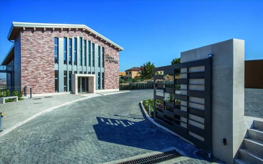 Facciata dell'hotel in mattoni con ingresso vetrato e cancello scorrevole grigio