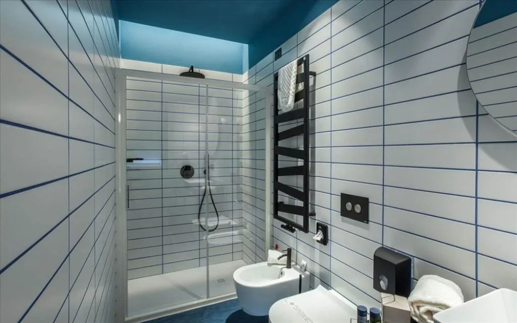 Bagno moderno con piastrelle bianche, doccia, bidet e soffitto blu