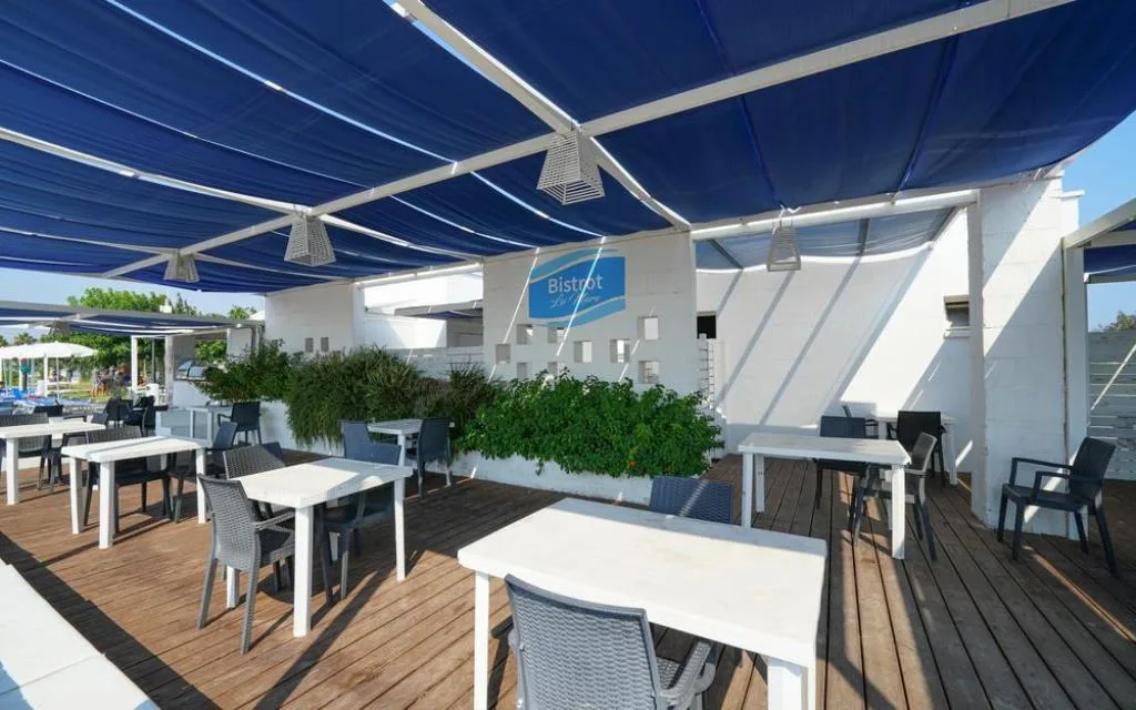 Terrazza bistrot con tavoli bianchi e copertura blu
