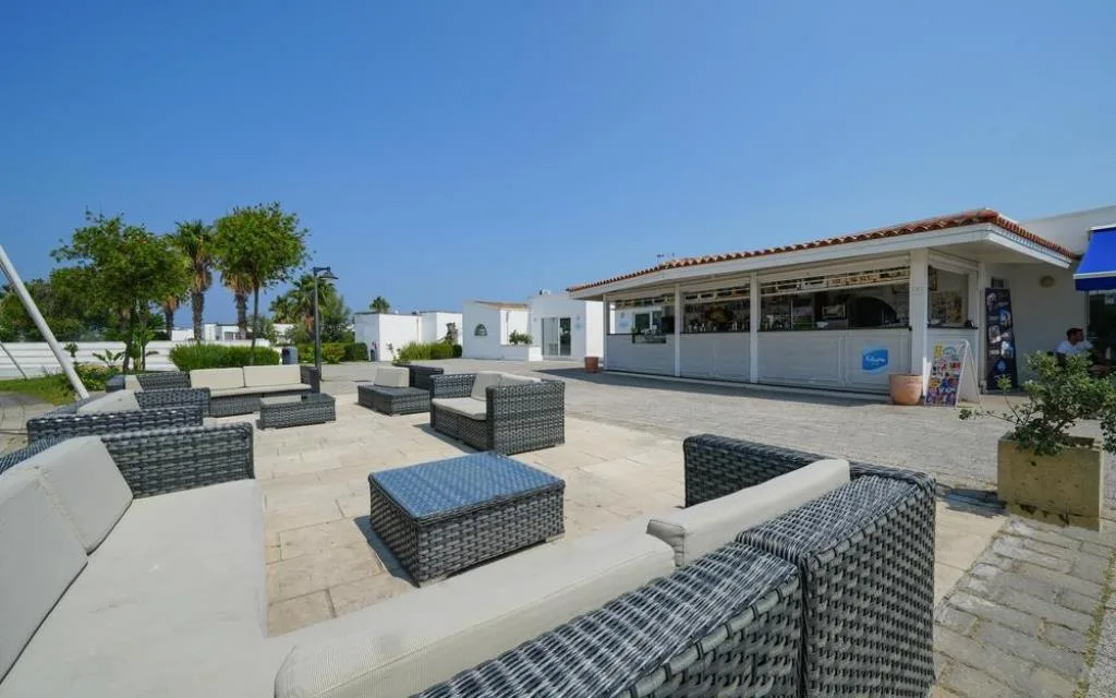 Area lounge esterna con divani in rattan e bar del resort