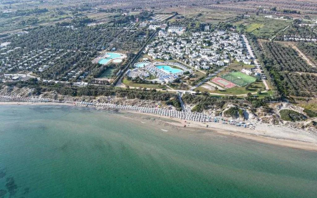Vista aerea del resort con piscine, campi sportivi e spiaggia sul mare