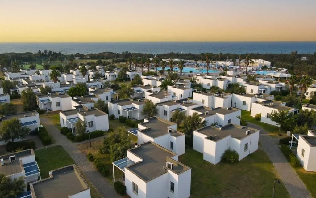 Vista aerea dei bungalow bianchi con piscina e mare al tramonto