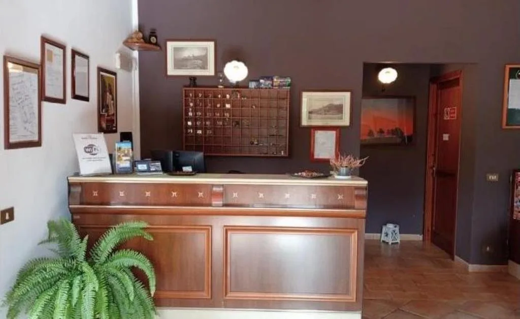 Reception dell'hotel con bancone in legno e quadri alle pareti
