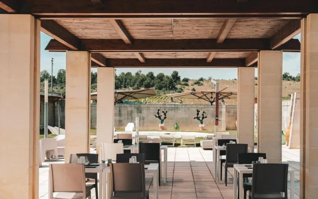 Terrazza ristorante coperta con tavoli e vista sulla campagna e sulla piscina