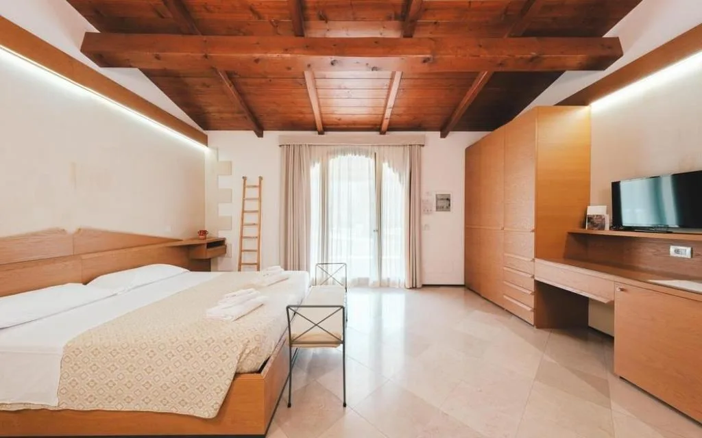 Ampia camera con letto matrimoniale, armadio in legno e soffitto travato