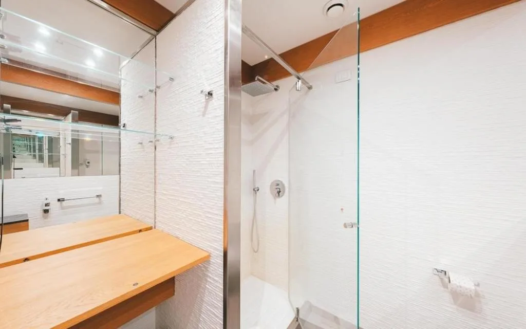 Bagno con doccia a vetro e piani in legno