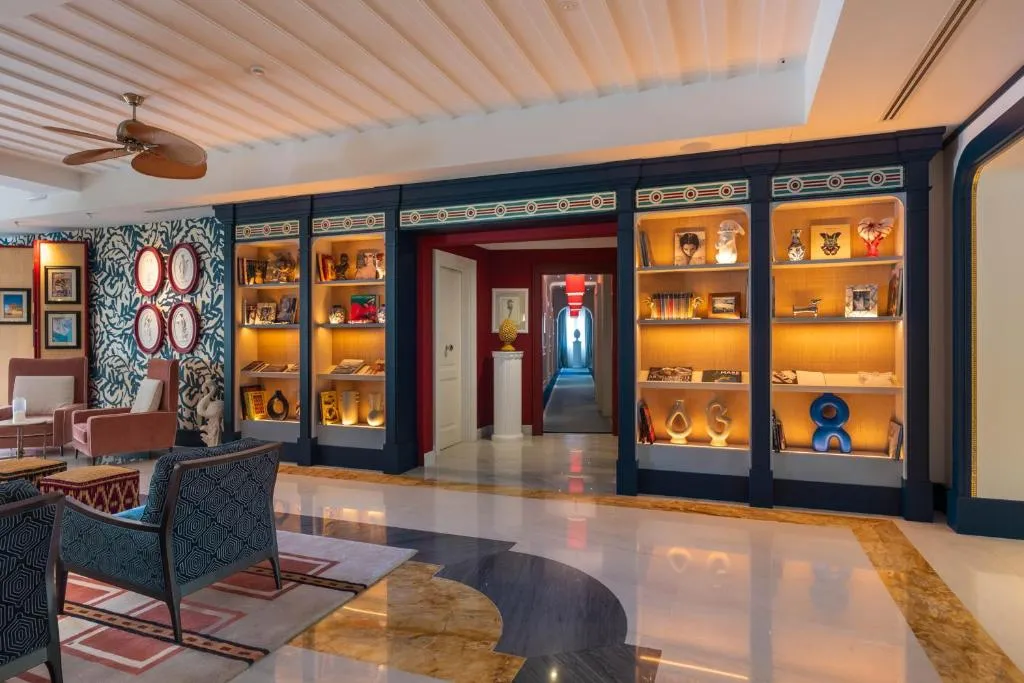 Corridoio interno con librerie illuminate, poltrone e pavimento in marmo