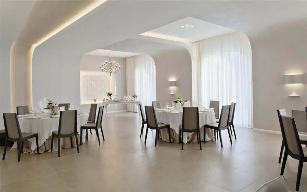 Sala ristorante moderna con tavoli rotondi apparecchiati, sedie grigie e illuminazione soffusa