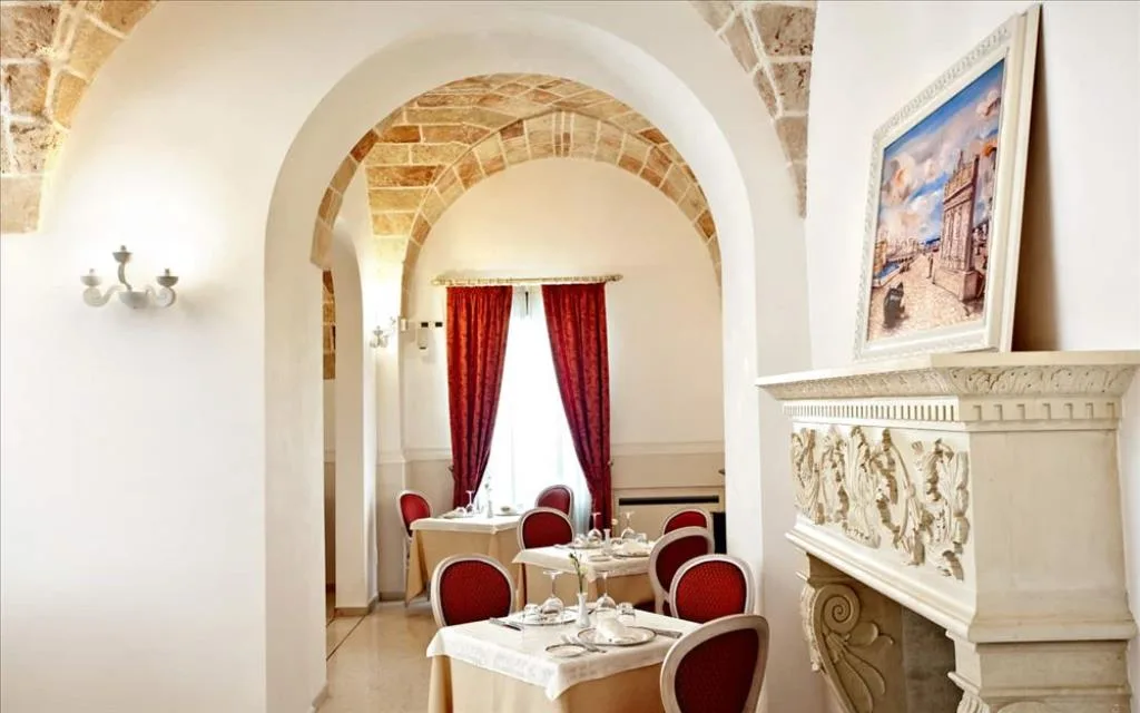 Sala ristorante con archi in pietra, camino decorativo, tende rosse e tavoli apparecchiati