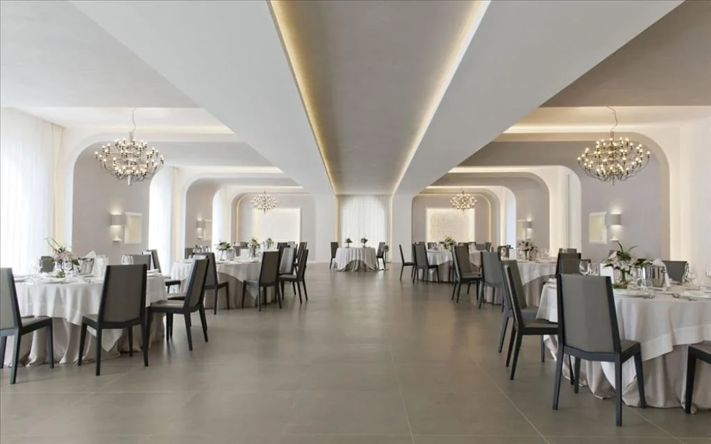 Elegante sala ristorante con lampadari, archi, tavoli apparecchiati e sedie grigie