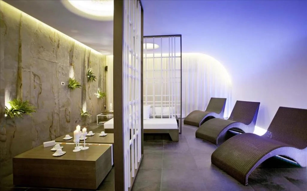 Zona relax spa con lettini in rattan, parete in pietra e candele, atmosfera rilassante