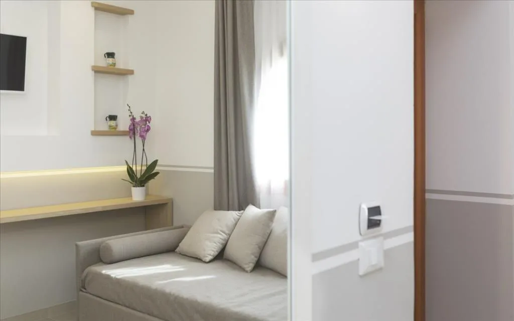 Angolo soggiorno di camera con divano beige, mensole in legno, orchidea e TV a parete