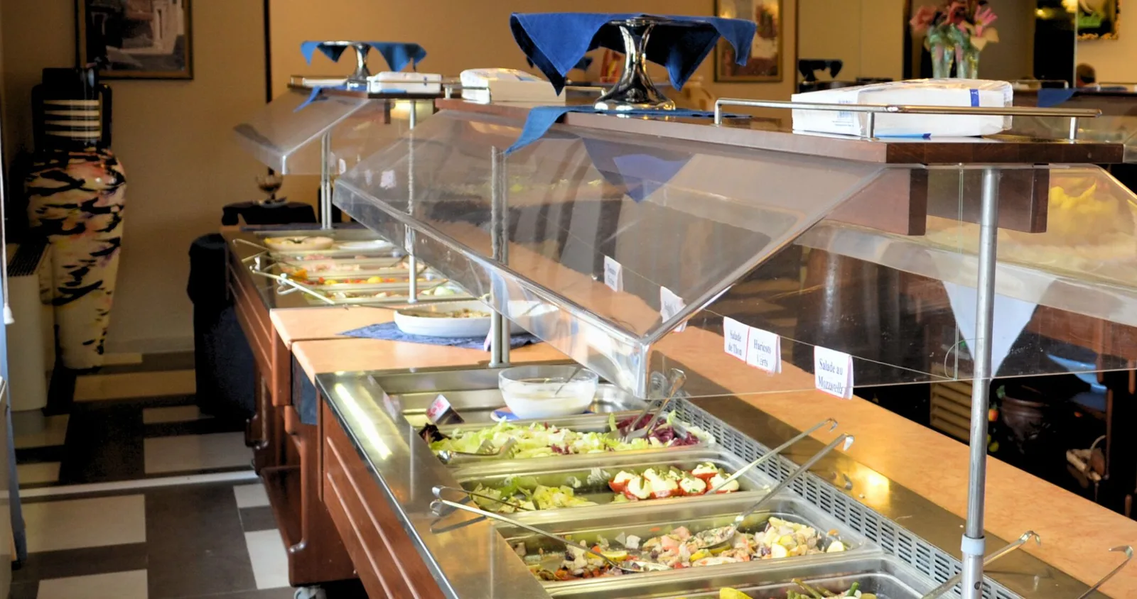 Buffet dell'hotel con vassoi di insalate e piatti freddi esposti sotto teche di protezione