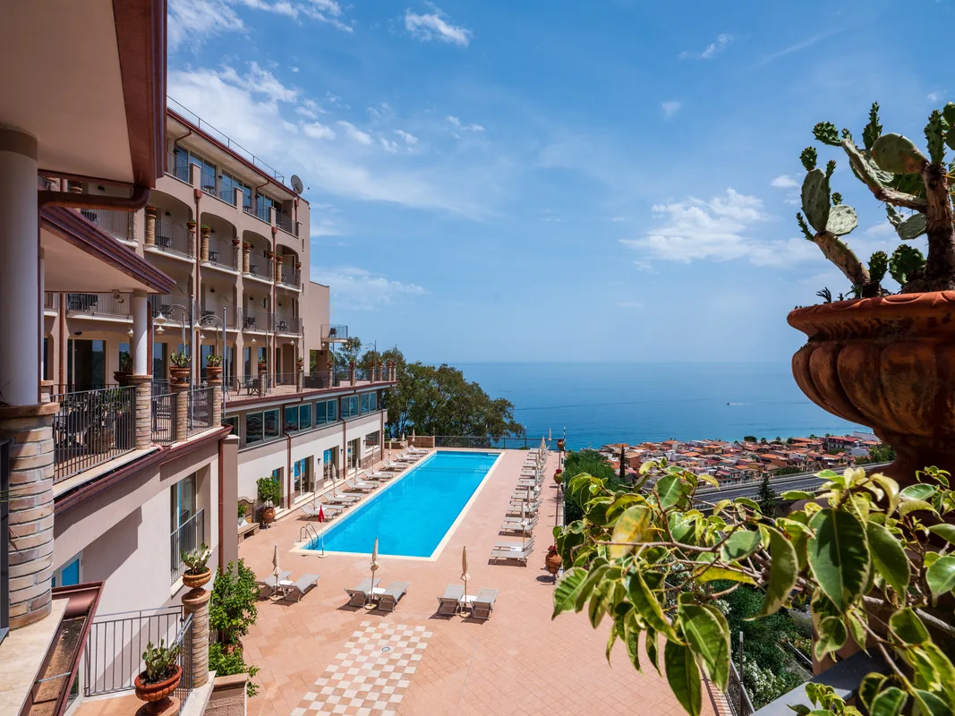 Piscina esterna dell'hotel con vista sul mare e sulla città costiera