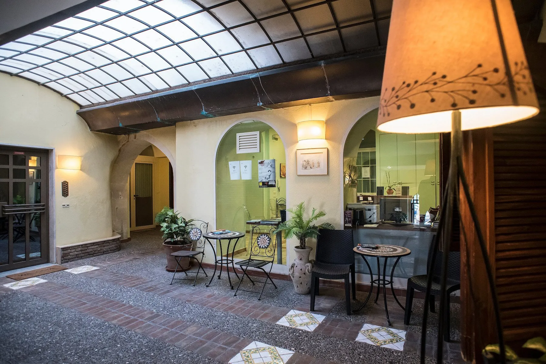 Cortile interno coperto con tetto in vetro, tavolini in ferro e reception