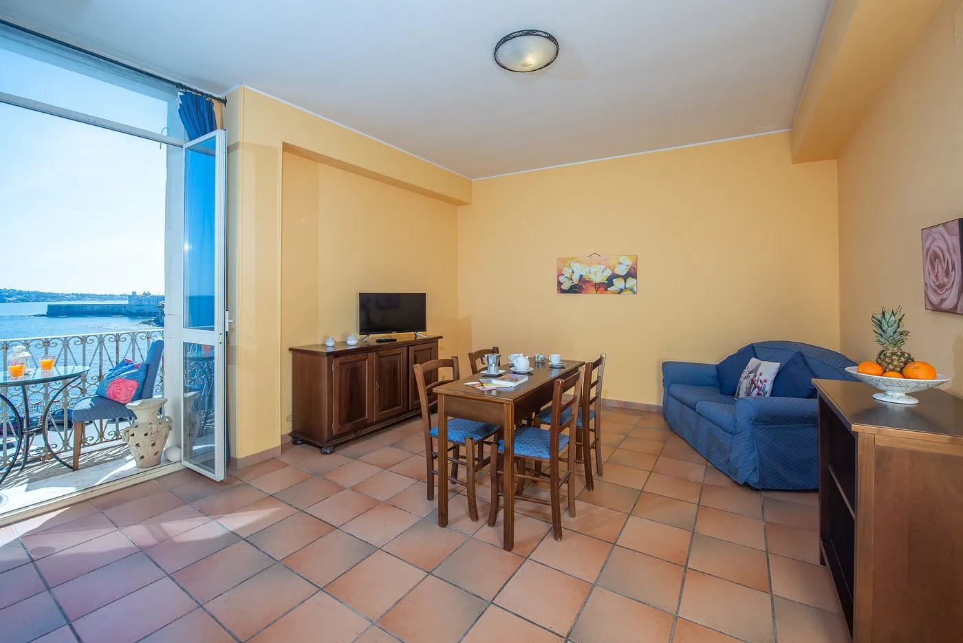 Soggiorno con balcone affacciato sul mare, divano blu e tavolo da pranzo