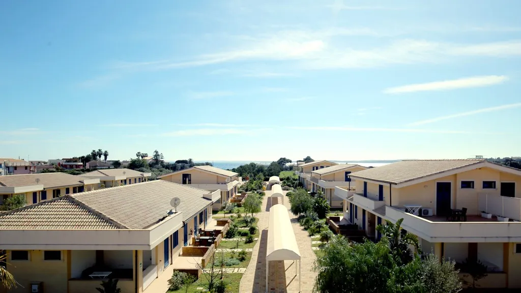 Vista panoramica del residence con villette, giardino centrale e mare sullo sfondo